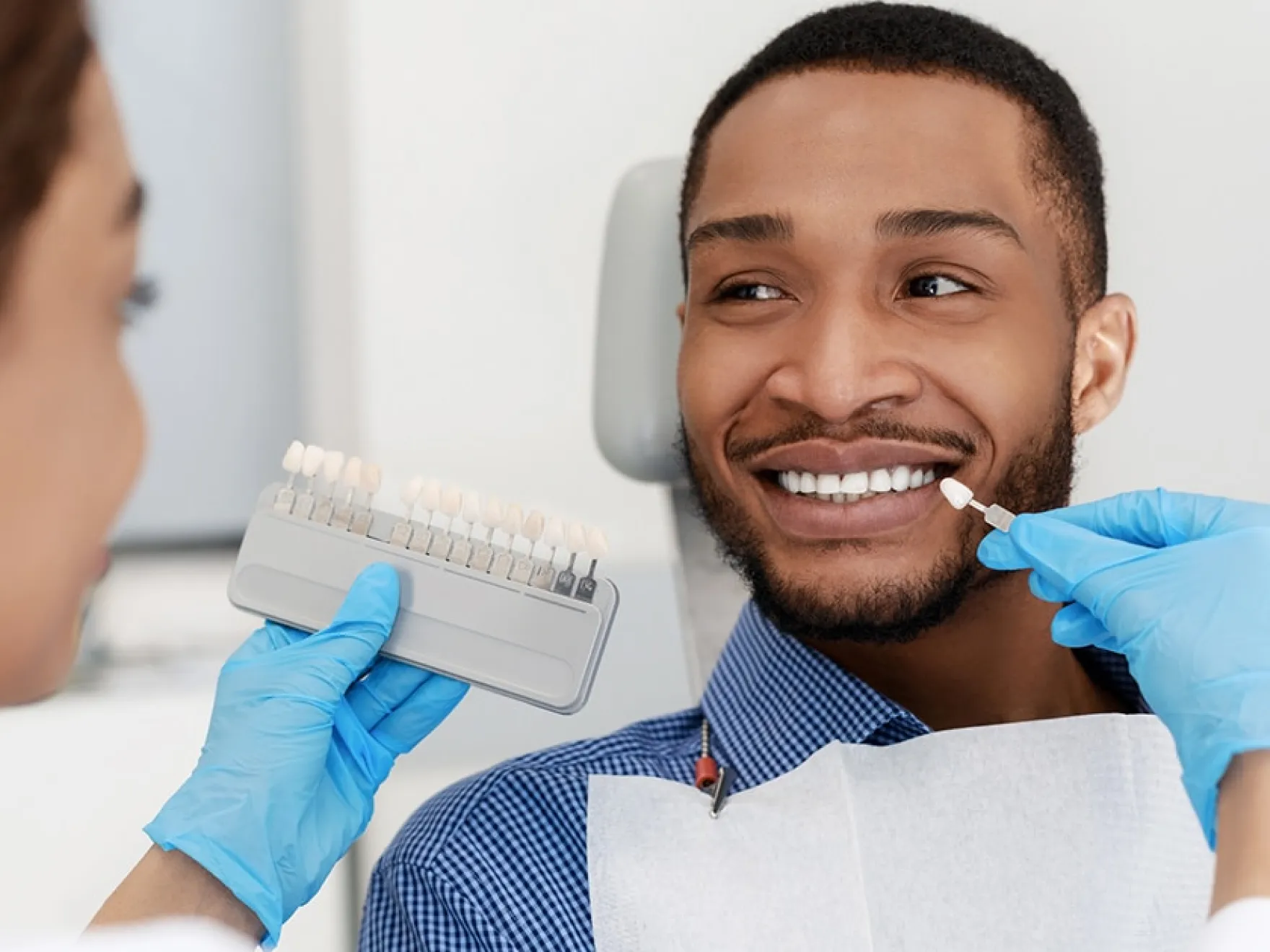 Man smiling while doctor shows him a filling that matches his teeth color